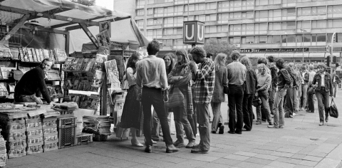 Wohnungssuchende an einem Zeitungskiosk vor dem Bahnhof Zoo, 1981. Wegen anhaltender Knappheit von Wohnraum war die systematische und sofortige Durchsicht der Immobilienanzeigen bei Erscheinen am Wochenende Routine. Üblich waren Gruppenaktivitäten, bei denen eine Telefonzelle freigehalten wurde, um möglichst weit oben auf einer Interessentenliste zu stehen. (Foto: Paul Glaser)