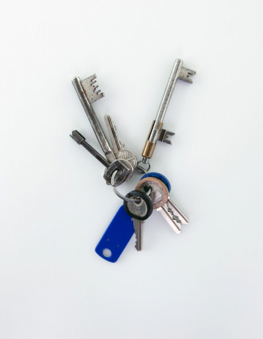 Durchsteckschlüssel (rechts im Bild, in einer Halterung). Mit einer speziellen Mechanik wurde, je nach Tageszeit, das Offenhalten oder Verschließen der Haustür erzwungen. Der seit Anfang des 20. Jahrhunderts verbreitete Schlüssel wurde nur in Berlin verwandt und seit den 1980er-Jahren sukzessive durch Sicherheitsschlösser mit Wechselsprechanlage ersetzt. Der Grund war unter anderem die Einsparung von Hauswarten, die die Türen morgens und abends umschalten mussten. Das Foto zeigt David Bowies Schlüsselbund aus der Zeit, als er in der Hauptstraße 155 in Berlin-Schöneberg wohnte (1976–1978). (Courtesy of The David Bowie Archive; vom Autor dieses Beitrags entdeckt in der Ausstellung »David Bowie« des Victoria & Albert Museum London, die vom 20.5. bis 24.8.2014 im Martin-Gropius-Bau in Berlin gezeigt wurde)