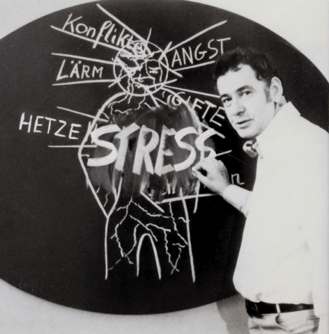 Frederic Vester erläutert anhand eines Tafelbildes »Stressgeschehen als Ausdruck des komplexen Netzes unserer Wechselbeziehungen mit der Umwelt«. (aus: Frederic Vester, Phänomen Streß. Wo liegt sein Ursprung, warum ist er lebenswichtig, wodurch ist er entartet?, Stuttgart 1976, Umschlagbild, Foto: Gabriele Oettingen; mit freundlicher Genehmigung)