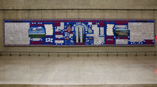 »The light of liberty will never be extinguished in our great land, it glows not in any one place but in the hearts & souls of all Americans everywhere«. Wandteppich mit Porträts der Getöteten und patriotischer Ikonographie (© National September 11 Memorial & Museum, Foto: Jin Lee)