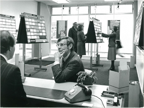 Beratungsideal im neu eingerichteten Jobcentre in den 1970er-Jahren, im Hintergrund die Job-Pinnwände (Department for Work and Pensions, <https://www.flickr.com/photos/dwpgovuk/15591606486/>, CC BY-NC-ND 2.0)