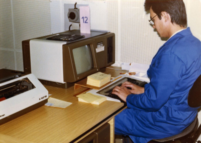 Mitarbeiter der MfS-Abteilung XII (Auskunft/Archiv) bei der »Datenumsetzung«, der Dateneingabe, vermutlich in das »System der automatischen Vorauswahl« (SAVO). Die SAVO-Datenbank enthielt in den 1980er-Jahren die wichtigsten Informationen der zentralen Personenkartei des MfS F 16 und ersetzte diese Papierkartei in der alltäglichen Überprüfungsarbeit weitgehend. (BStU, MfS, Abt. XII, Fo 0093, Bild 2)