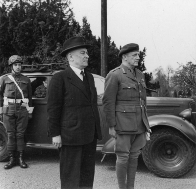 Der belgische Premierminister Hubert Pierlot (Mitte, begleitet vom britischen Major General Robert Grice Sturges, rechts) wird bei einem offiziellen Besuch in einem Gruppenhauptquartier der Special Services mit militärischen Ehren empfangen, 21. April 1944.(Wikimedia Commons; Imperial War Museum/Public Domain; Foto: Lt. Tanner, War Office official photographer) Der belgische Premierminister Hubert Pierlot (Mitte, begleitet vom britischen Major General Robert Grice Sturges, rechts) wird bei einem offiziellen Besuch in einem Gruppenhauptquartier der Special Services mit militärischen Ehren empfangen, 21. April 1944.(Wikimedia Commons; Imperial War Museum/Public Domain; Foto: Lt. Tanner, War Office official photographer)