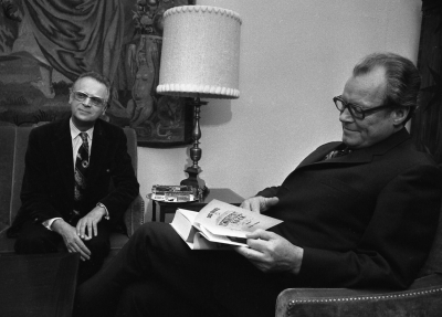 Auch der Kanzler liest Kishon: Besuch des Schriftstellers bei Willy Brandt, 12. März 1974. Der Bundeskanzler blättert im »Großen Kishon-Buch«. (picture-alliance/AP Images/Klaus Schlagmann)