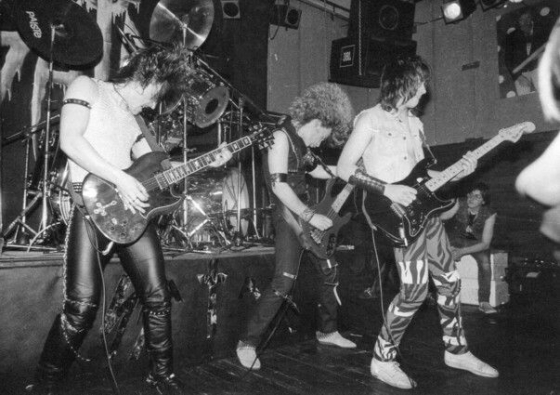 Die Band Satan aus South Shields während eines Konzerts im »Denim and Leather«-Look und mit Choreographie der Gitarristen (um 1982) (http://NWOBHM.com/satan/)