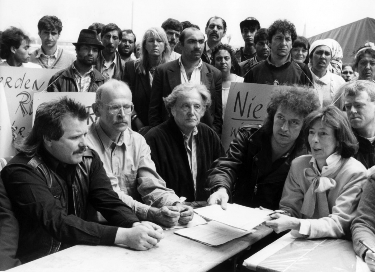 Kundgebung in Düsseldorf für das Bleiberecht von Roma, 19. Juli 1991. Die prominenten Unterstützer im Vordergrund sind Tommy Engel, Sänger der »Bläck Fööss«, die Publizisten Günter Wallraff und Ralph Giordano, BAP-Sänger Wolfgang Niedecken sowie Hedwig Neven DuMont, Ehefrau des Verlegers Alfred Neven DuMont. Eine Roma-Gruppe mit Plakaten bleibt im Hintergrund. (picture-alliance/Fotoreport-DB) Kundgebung in Düsseldorf für das Bleiberecht von Roma, 19. Juli 1991. Die prominenten Unterstützer im Vordergrund sind Tommy Engel, Sänger der »Bläck Fööss«, die Publizisten Günter Wallraff und Ralph Giordano, BAP-Sänger Wolfgang Niedecken sowie Hedwig Neven DuMont, Ehefrau des Verlegers Alfred Neven DuMont. Eine Roma-Gruppe mit Plakaten bleibt im Hintergrund. (picture-alliance/Fotoreport-DB)