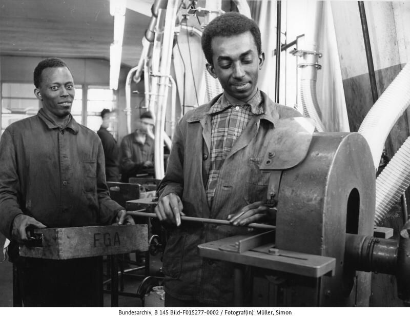 10. April 1963, Bad Godesberg-Mehlem, afrikanische Studenten der Technischen Hochschule Hannover in den Ringsdorff-Werken. Damalige Bildbeschreibung: »Ausländische Praktikanten in der Bundesrepublik Deutschland: Die Bundesregierung, Länder und Kommunen haben in den letzten Monaten zunehmend Programme für die Fortbildung von Praktikanten aufgestellt oder sonstige finanzielle Förderung gewährt. Praktikanten kamen aus Asien, Afrika und Südamerika. Um den Erfolg der Fortbildung zu erhöhen, werden schon möglichst gut vorgebildete Praktikanten ausgewählt. Die Ausbildungsprogramme werden verbessert, indem zweckvoll abgestimmte Praktika in mehreren Lehrgängen ergänzt werden. Im Jahre 1962 wurden in Zusammenarbeit mit den Landesarbeitsämtern und Arbeitsämtern 2.613 Praktikanten vermittelt.« (Bundesarchiv, B 145 Bild-F015277-0002, Foto: Simon Müller) 10. April 1963, Bad Godesberg-Mehlem, afrikanische Studenten der Technischen Hochschule Hannover in den Ringsdorff-Werken. Damalige Bildbeschreibung: »Ausländische Praktikanten in der Bundesrepublik Deutschland: Die Bundesregierung, Länder und Kommunen haben in den letzten Monaten zunehmend Programme für die Fortbildung von Praktikanten aufgestellt oder sonstige finanzielle Förderung gewährt. Praktikanten kamen aus Asien, Afrika und Südamerika. Um den Erfolg der Fortbildung zu erhöhen, werden schon möglichst gut vorgebildete Praktikanten ausgewählt. Die Ausbildungsprogramme werden verbessert, indem zweckvoll abgestimmte Praktika in mehreren Lehrgängen ergänzt werden. Im Jahre 1962 wurden in Zusammenarbeit mit den Landesarbeitsämtern und Arbeitsämtern 2.613 Praktikanten vermittelt.« (Bundesarchiv, B 145 Bild-F015277-0002, Foto: Simon Müller)